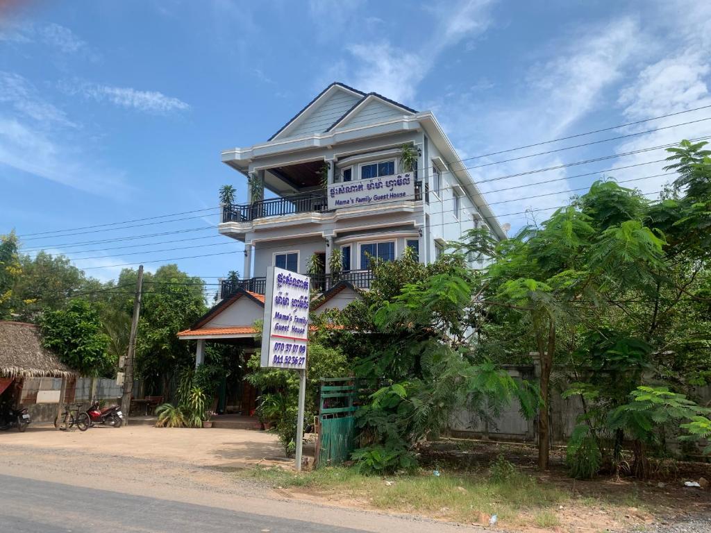une maison blanche avec un panneau devant elle dans l'établissement Mama's Family Guesthouse, à Kampot