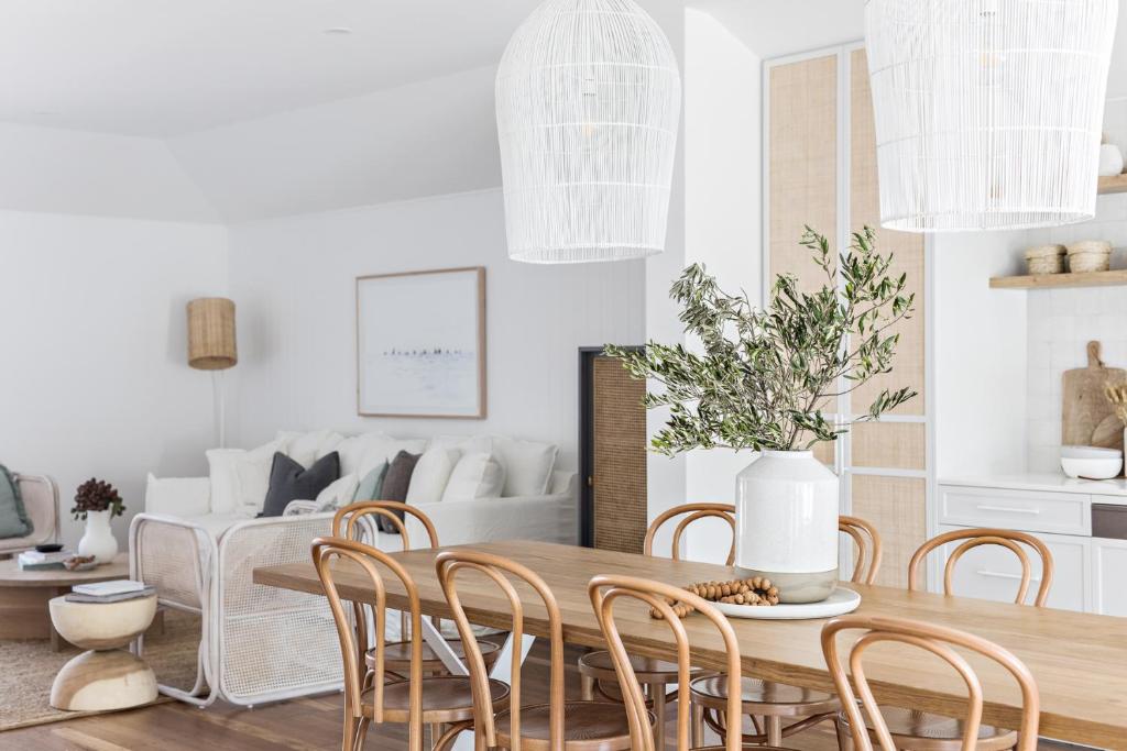 a living room with a wooden table and chairs at Cape Beach House in Byron Bay