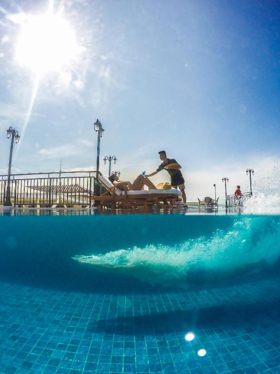 um homem sentado num banco ao lado de uma piscina em Feliz Hotel Boracay em Boracay