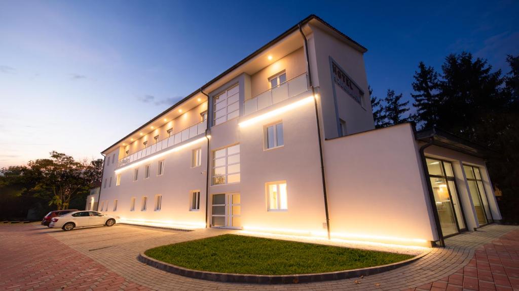 Biały budynek z oświetleniem na boku w obiekcie Hotel Szeghalom w mieście Szeghalom