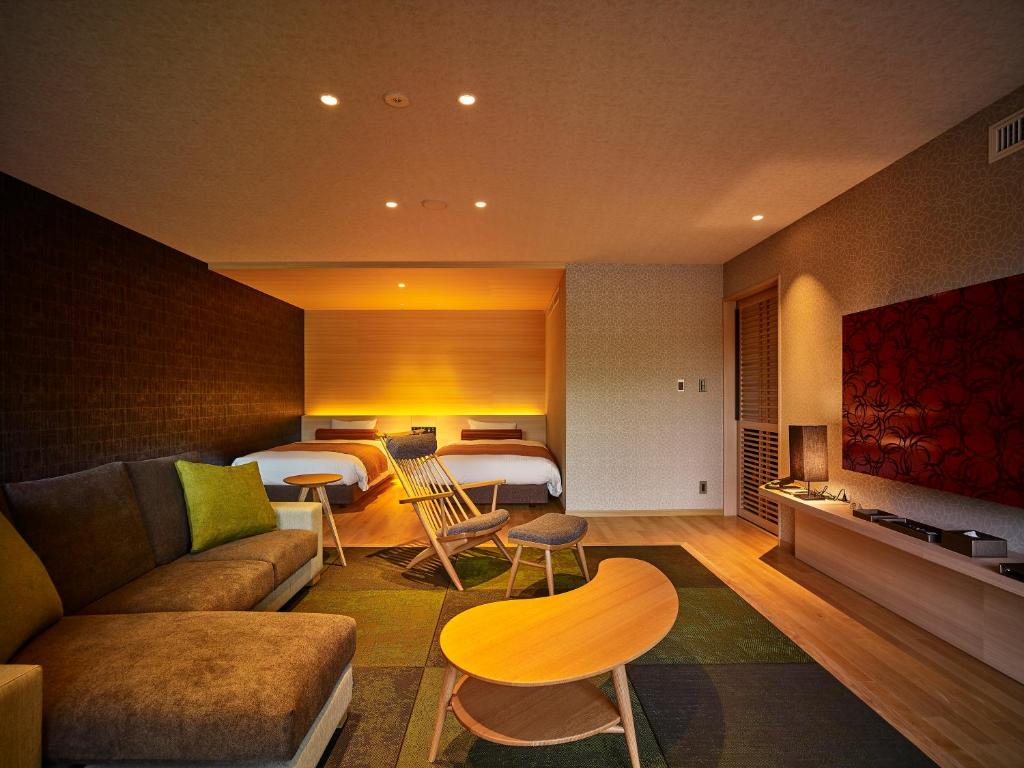 a living room with a couch and a room with two beds at Kumano-bettei Nakanoshima in Katsuura