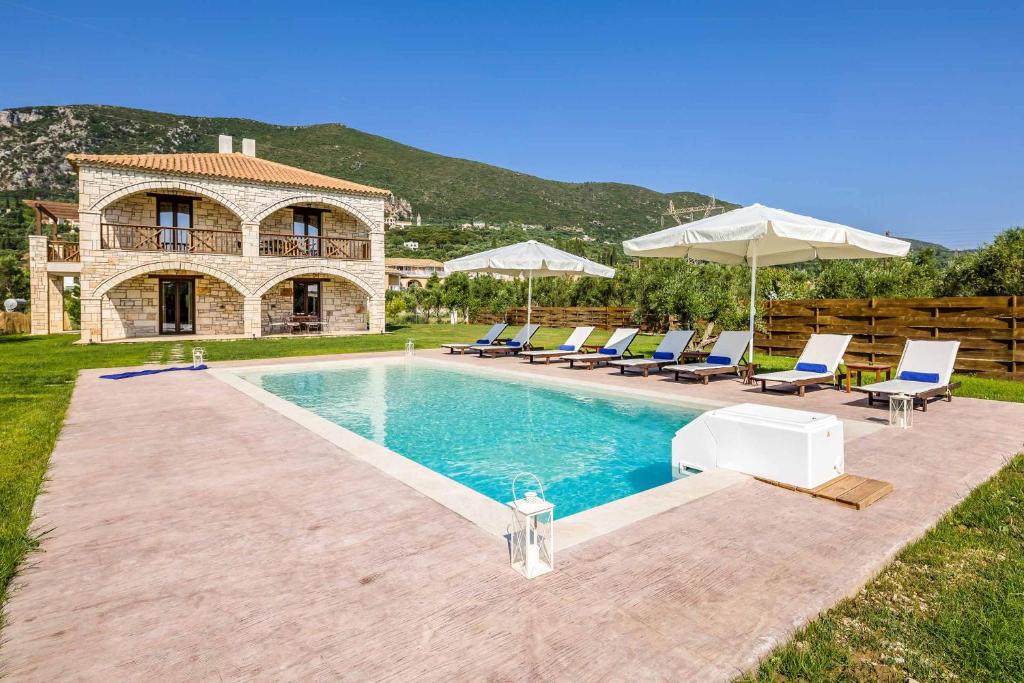 - une piscine avec des chaises et des parasols en face d'une maison dans l'établissement Villa Stagio, à Alykes