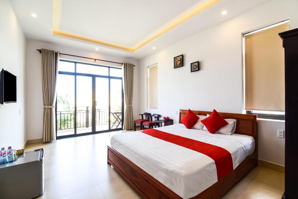 a bedroom with a large bed and a large window at OYO 473 Suburban Villa in Hoi An