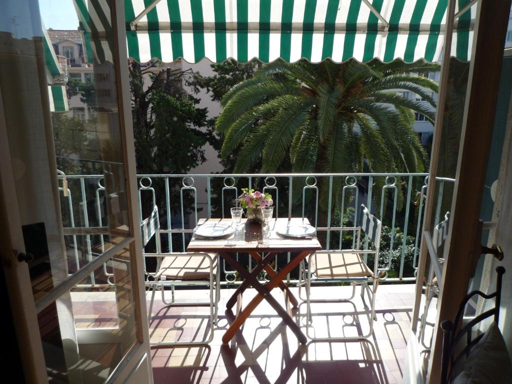 une table et des chaises sur un balcon avec un palmier dans l'établissement Centre, deux pièces, calme, terrasse plein sud, à Nice