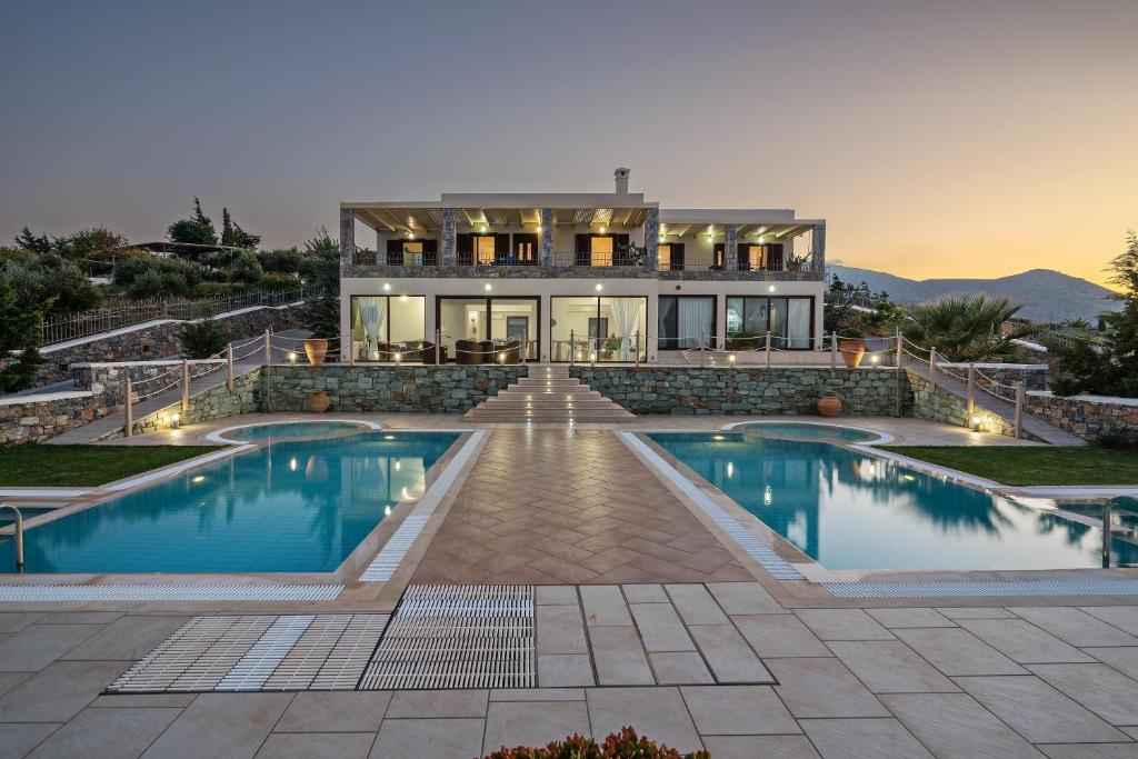 a house with a swimming pool in front of a house at Villas Anemomilos in Agia Pelagia