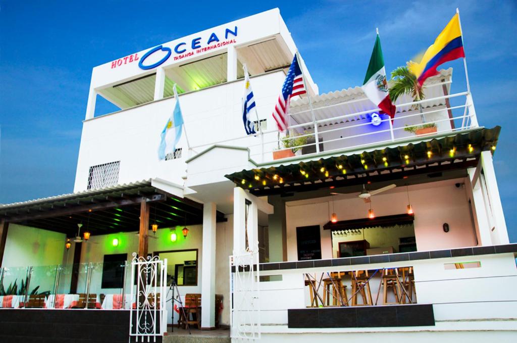 a white building with flags in front of it at Hotel Ocean Taganga Internacional in Taganga