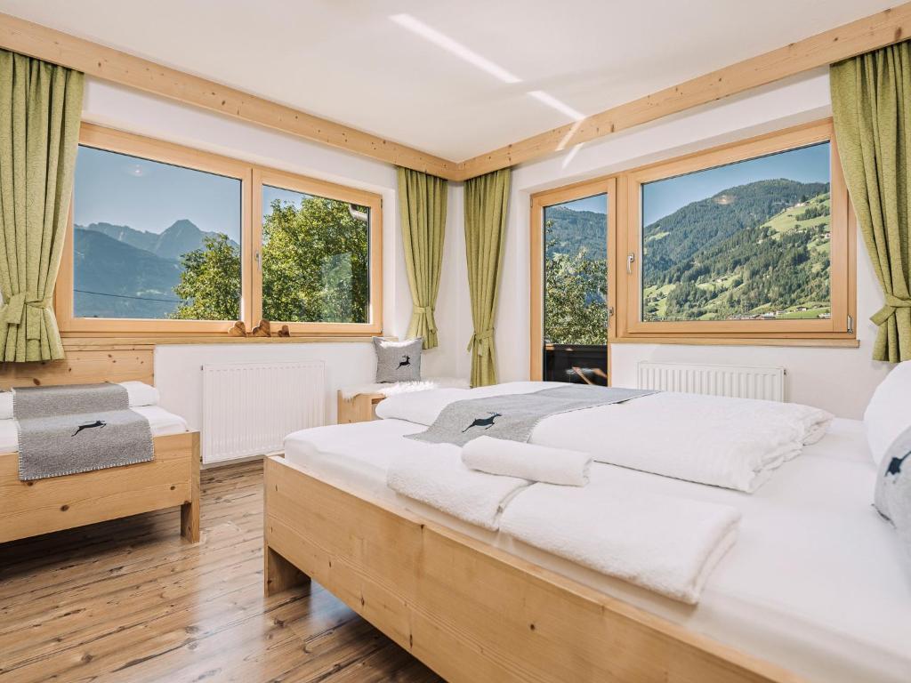 a bedroom with two beds and large windows at Apartment Aschenwald Elisabeth in Ramsau im Zillertal