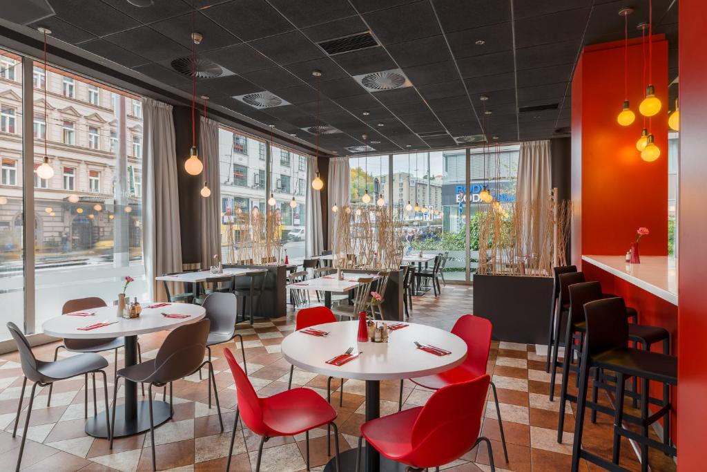 restauracja z białymi stołami i czerwonymi krzesłami w obiekcie Ibis Praha Mala Strana w Pradze