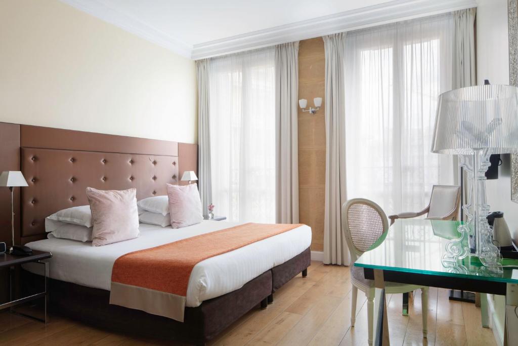パリにあるル 123 エリゼ アストテルのベッド、デスク、ベッドが備わるホテルルームです。
