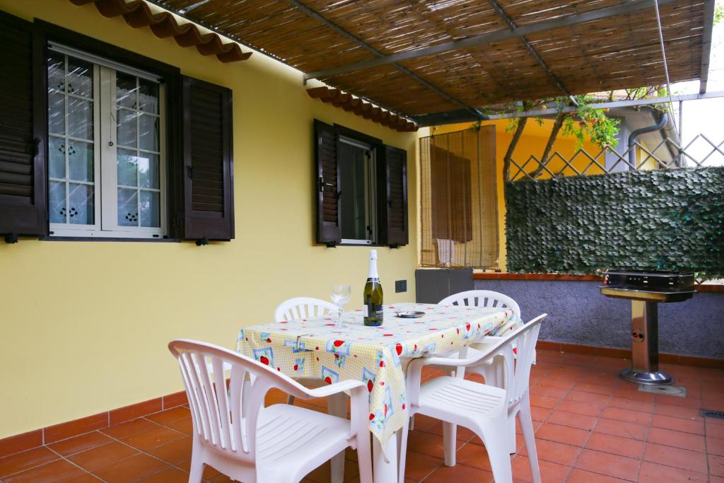 uma mesa com cadeiras brancas e uma garrafa de vinho em Casa Giulia by HelloElba em Marina di Campo