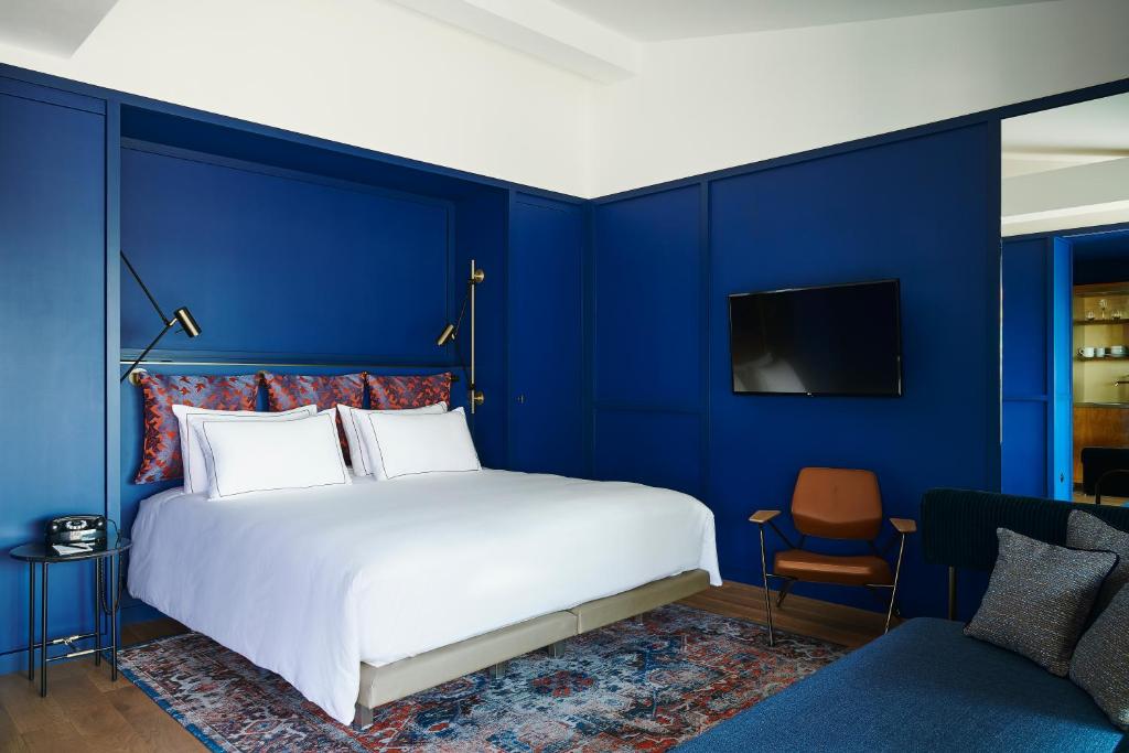 um quarto azul com uma cama e uma cadeira em Hôtel Le Ballu em Paris