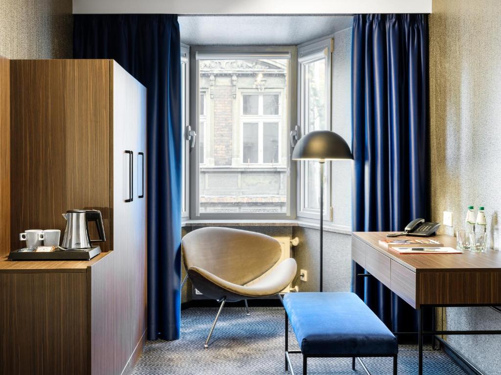a room with a desk and a chair and a window at Hotel Logos Kraków in Krakow