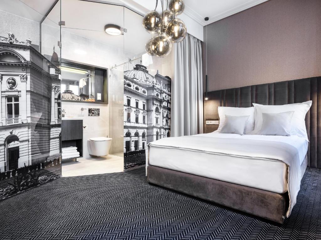 a bedroom with a large white bed and a bathroom at Hotel Logos Kraków in Krakow