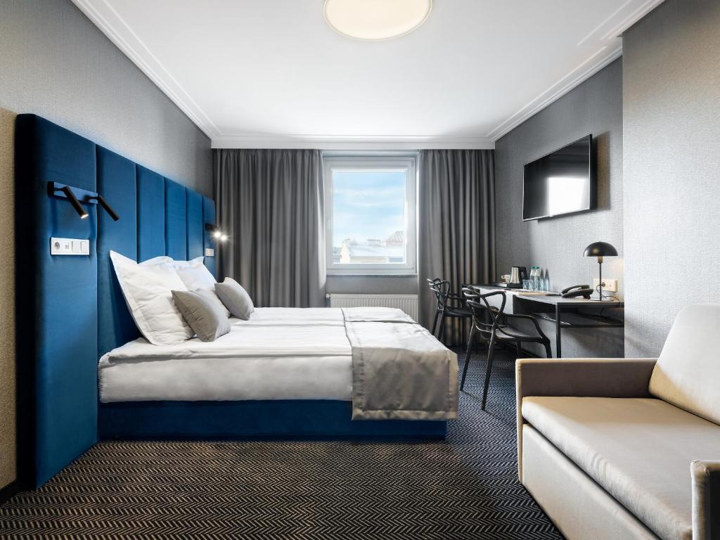 a hotel room with a large bed and a desk at Hotel Logos Kraków in Krakow