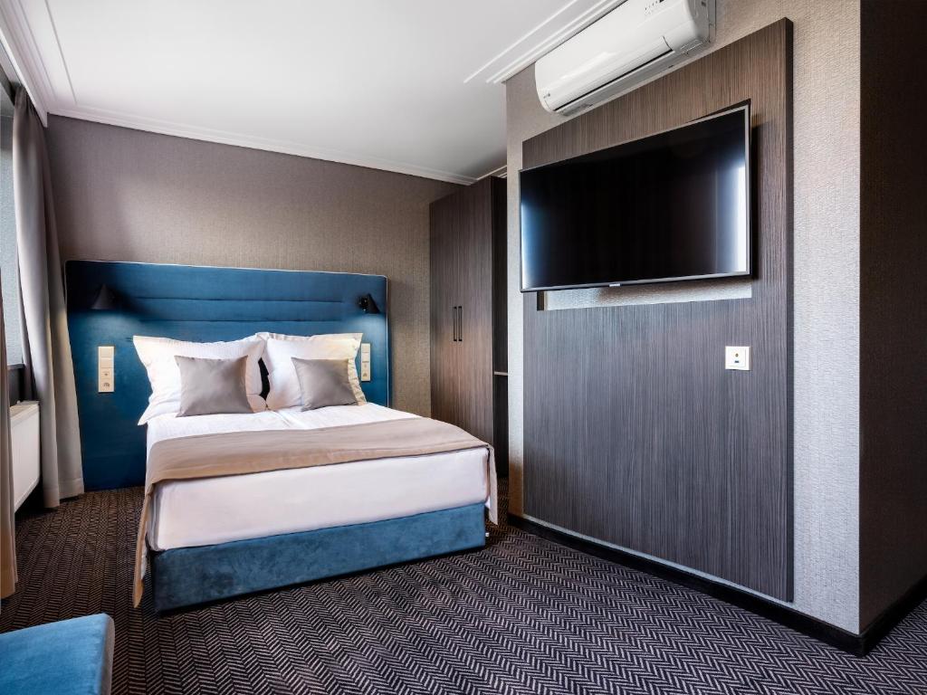 a bedroom with a bed and a flat screen tv at Hotel Logos Kraków in Krakow