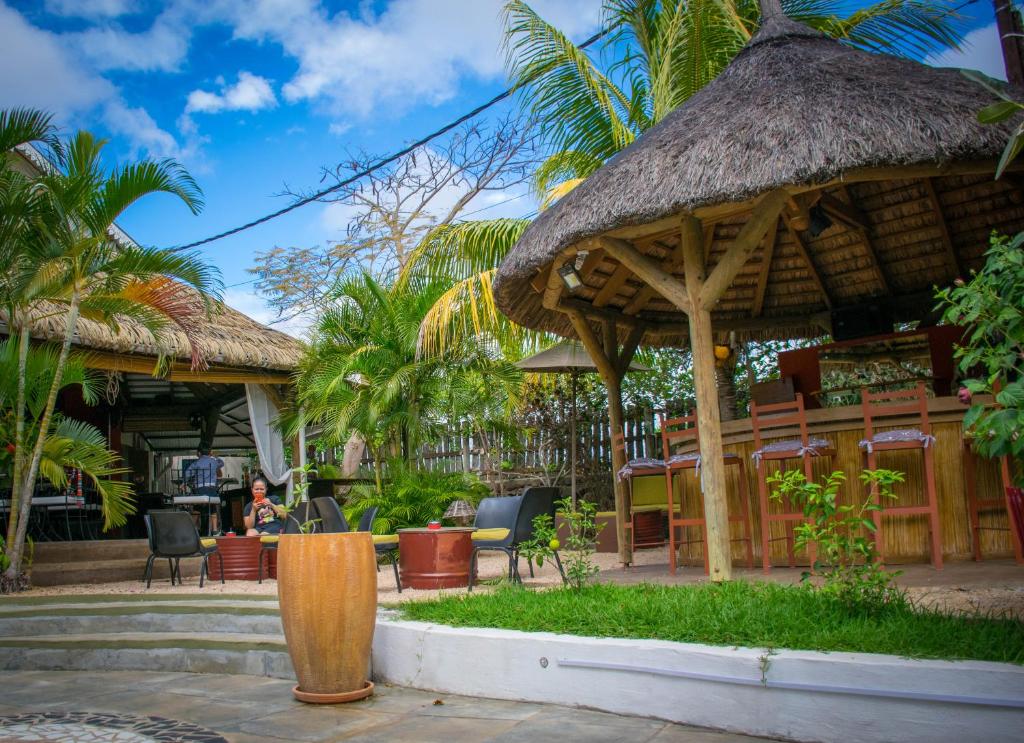 un restaurant avec toit de chaume, table et chaises dans l'établissement VILLAVAGUE Lodge, à Albion