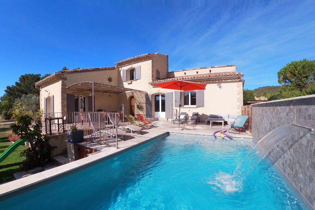 a villa with a swimming pool in front of a house at Le Panorama des Alpilles in Aureille