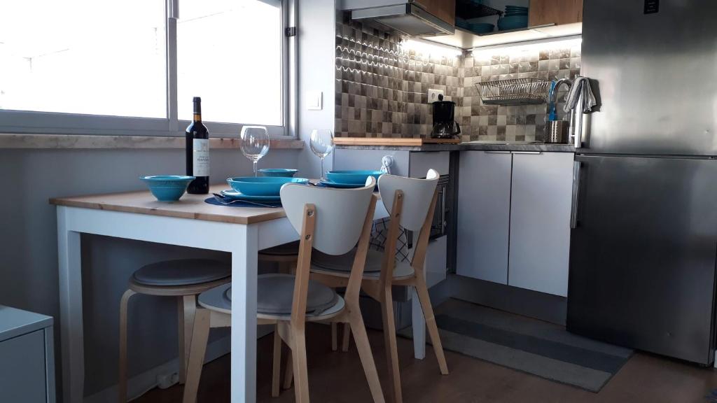 cocina con mesa, sillas y nevera en Apartamento Blue dream, en Sesimbra