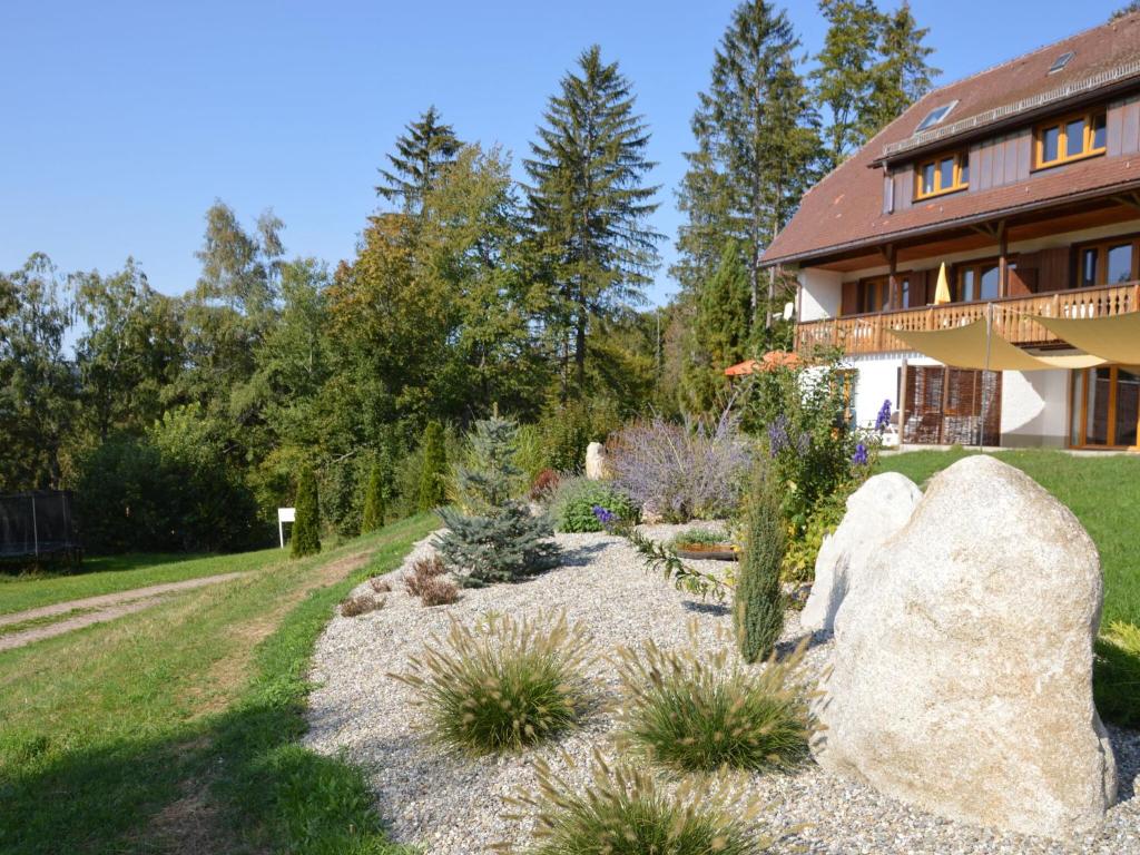 un jardín frente a una casa con una roca grande en Apartment in the Black Forest with balcony, en Urberg