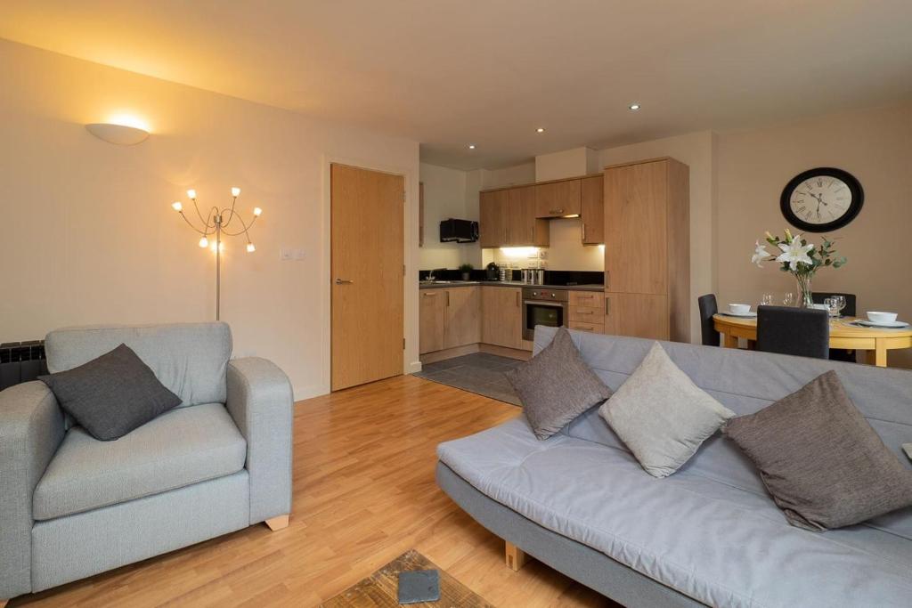 ノッティンガムにあるStylish & Cosy Apartmentのリビングルーム(ソファ2台付)、キッチンが備わります。