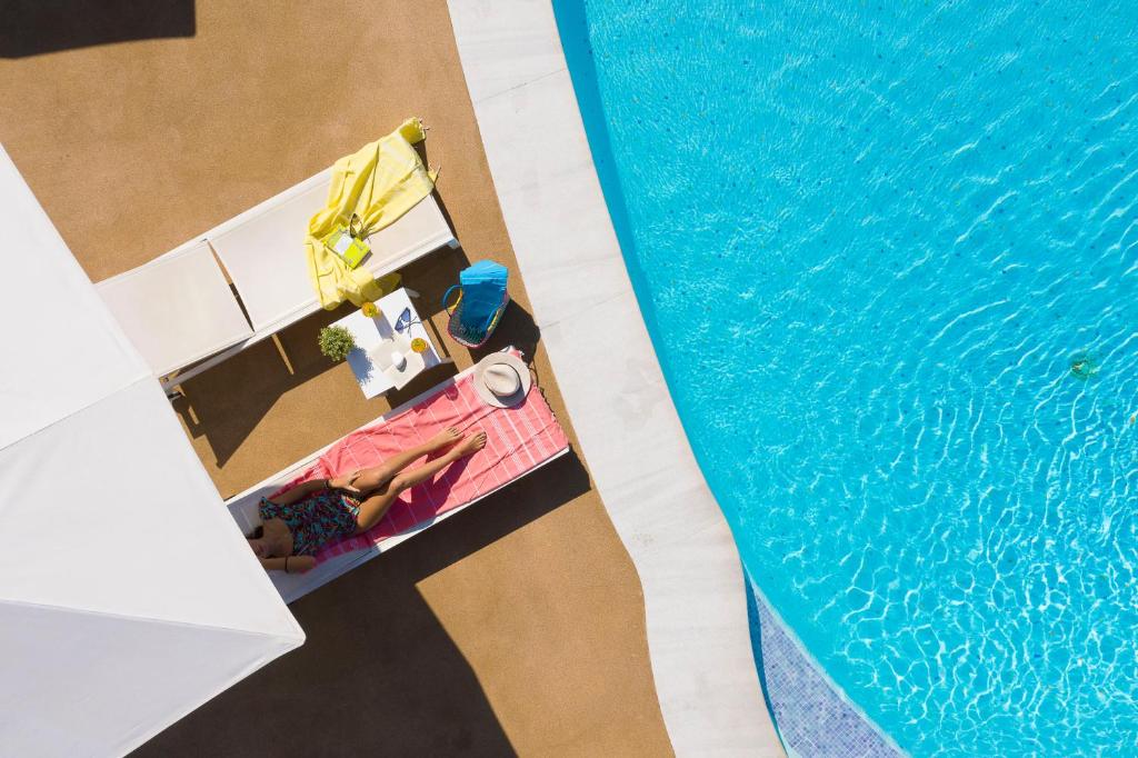 an overhead view of a swimming pool with a woman in a bikini next to it at Mandraki Village Boutique Hotel in Koukounaries
