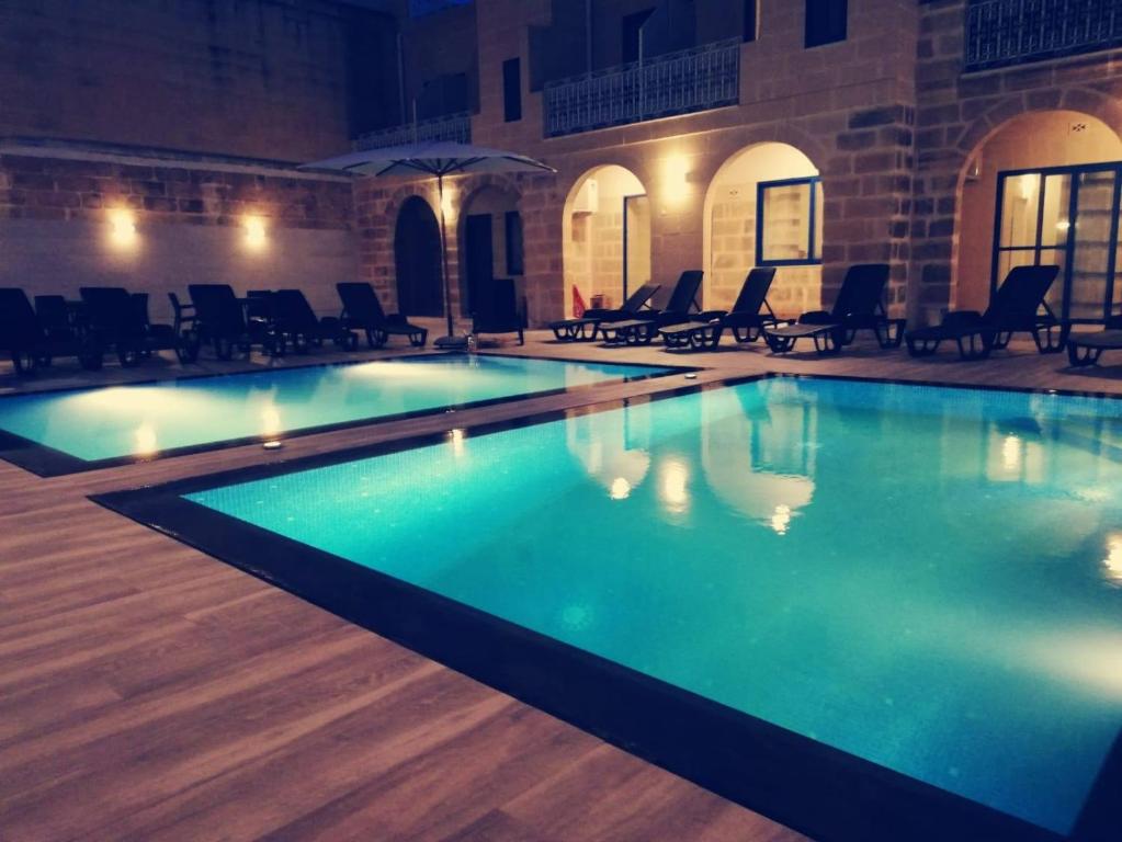 a swimming pool with blue water in a building at Fiftyfour West Boutique Living in Għarb