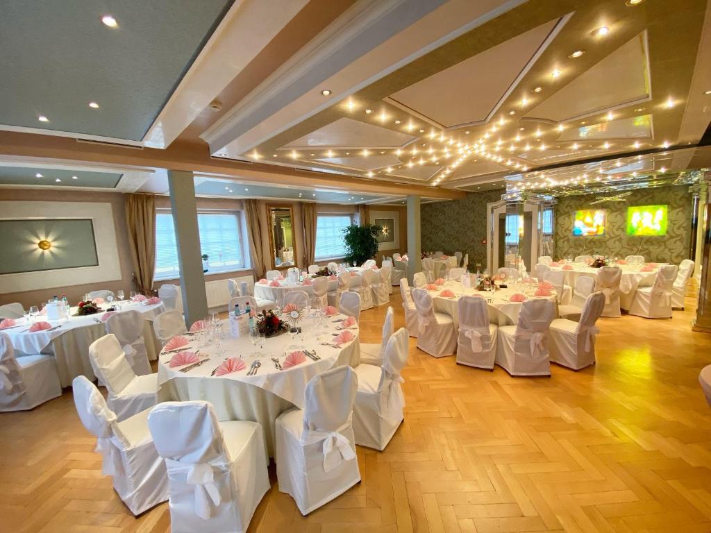 a banquet hall with white tables and white chairs at Hotel zur goldenen Sonne in Usingen