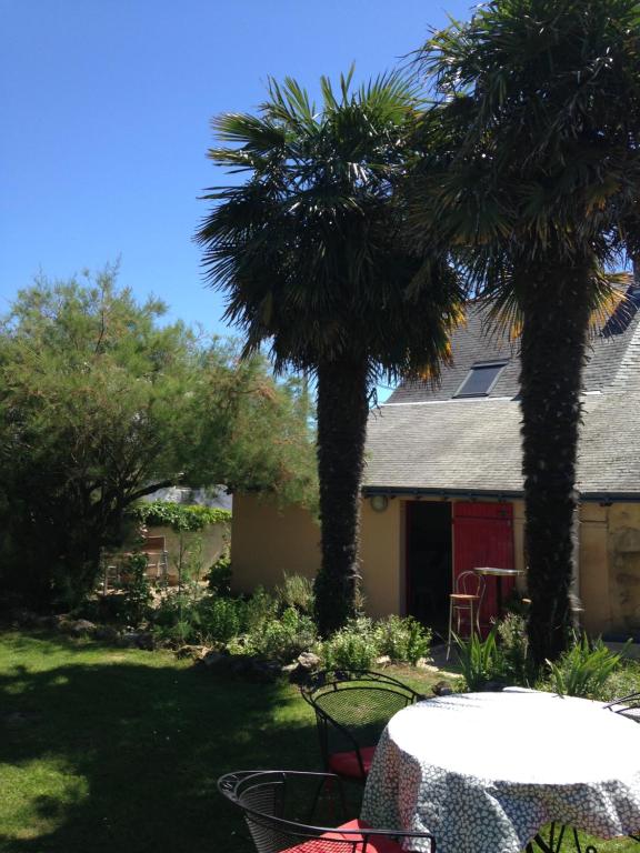 two palm trees in a yard with a table and chairs at Entre Mer et Marais Salants in Guérande
