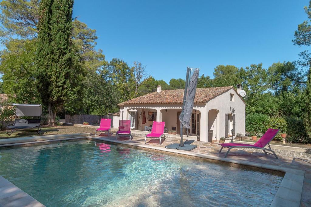 Una piscina con sillas rosas y una casa. en Villa les Pins, en Callas