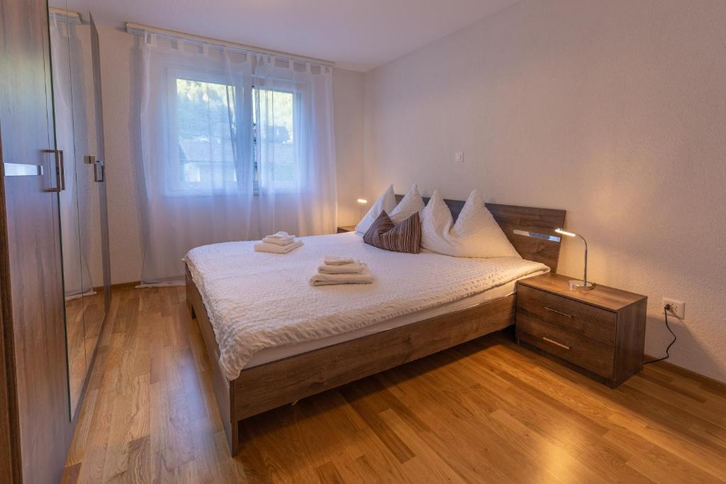 een slaapkamer met een bed met witte lakens en een raam bij Chalet Gousweid- Harder Apartment in Wilderswil