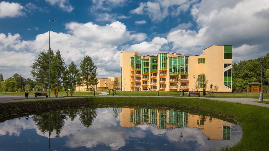 a building and a pond in front of a building at AMAKS Krasnaya Pakhra Resort in Krasnoye