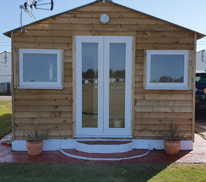 uma pequena casa com duas janelas e uma porta em Milas Place em Leysdown-on-Sea