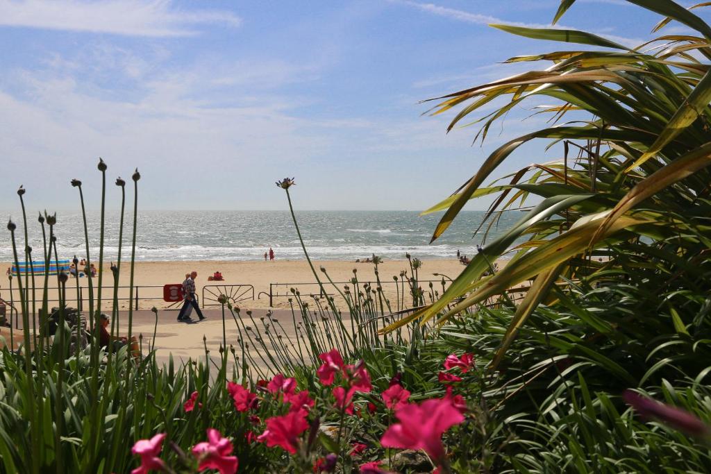a beach with people walking on the sand and the ocean at The Canford in Poole