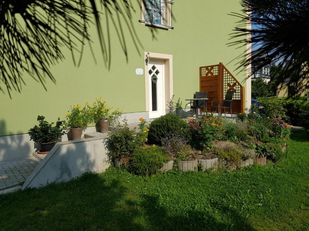 une maison verte avec une terrasse agrémentée de plantes dans la cour dans l'établissement Ferienwohnung Karlguth, à Neustadt in Sachsen