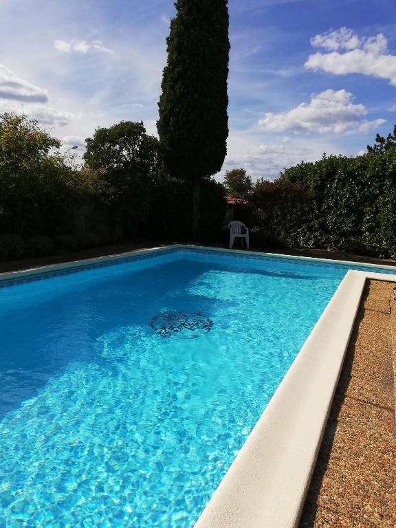 une piscine avec de l'eau bleue dans une cour dans l'établissement Maison D architecte chez Huguette, à Villalier