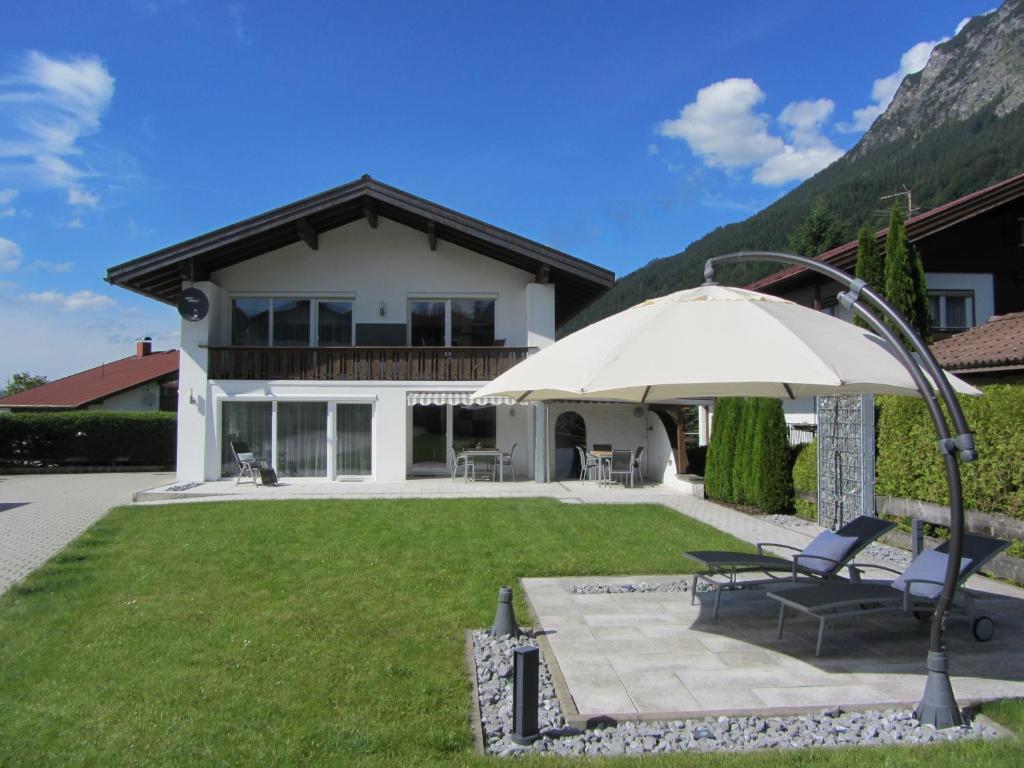 Cette maison dispose d'une terrasse avec un parasol. dans l'établissement Alpenflair Ferienwohnungen Whg 307 Edel-Weiß, à Oberstdorf