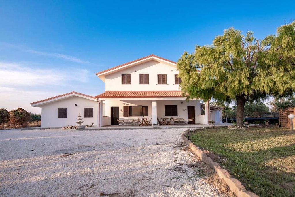 una casa blanca con un árbol y una entrada en Villa Andrea San Lorenzo, en Noto