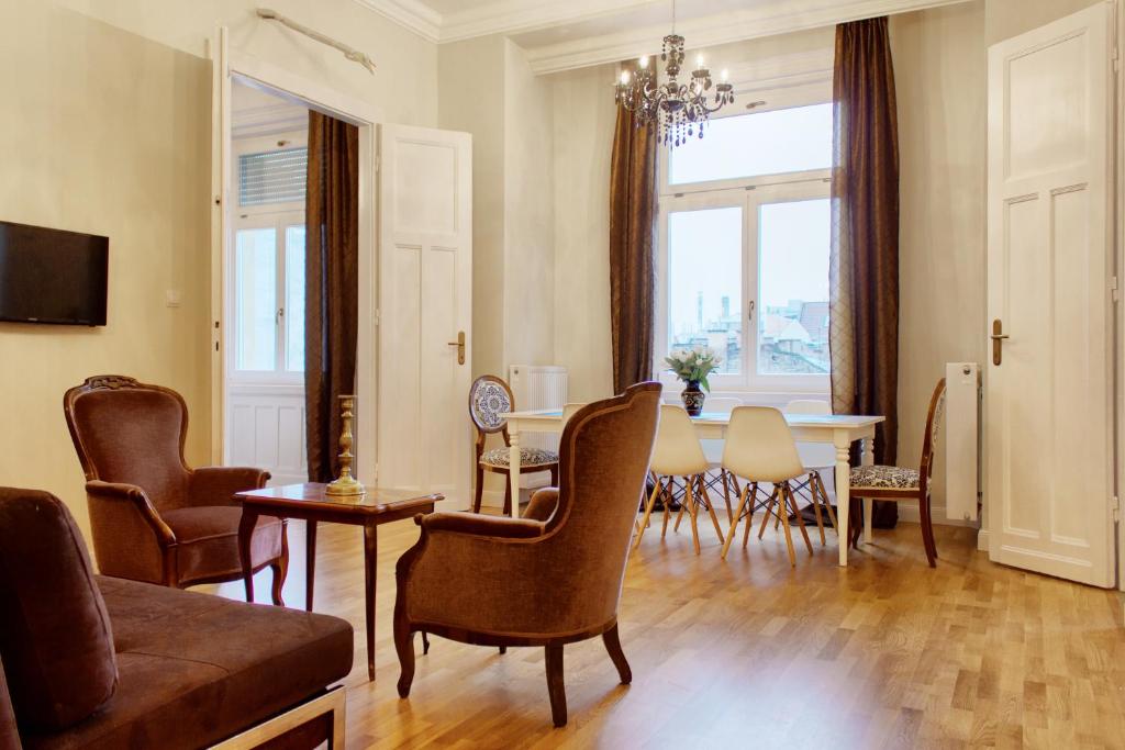 een woonkamer met een tafel en stoelen bij 4BR , 3BHR with AC at the OPERA in Boedapest