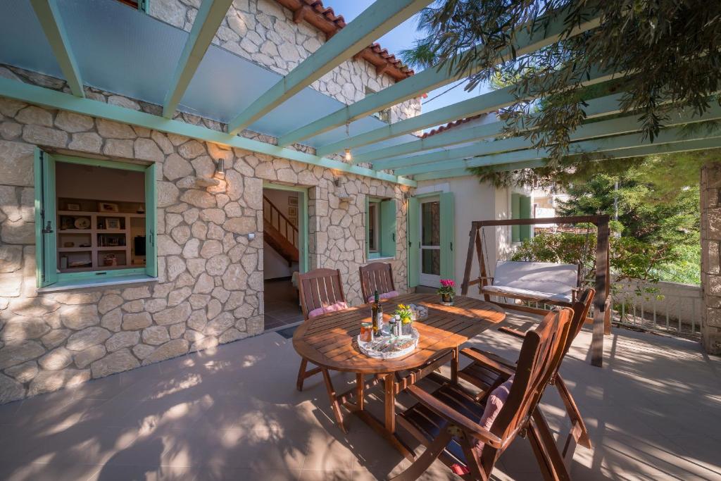 a patio with a wooden table and chairs at My Little House - Family House with Private Terrace in Aegina Town