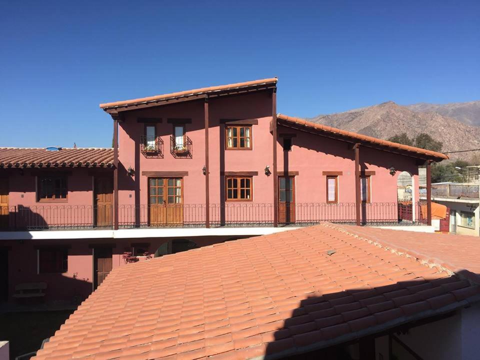 a large pink house with a red tile roof at Altos de la Pacha in Cafayate