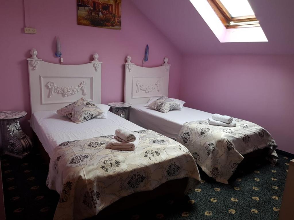 two beds with towels on them in a room at Hotel Darosy in Arad