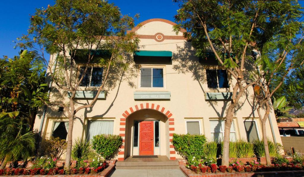 Casa blanca con puerta roja y árboles en Santa Paula Inn, en Santa Paula