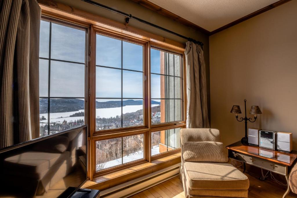 a room with a large window with a chair and a desk at L'Équinoxe Rendez-Vous Mont-Tremblant in Mont-Tremblant