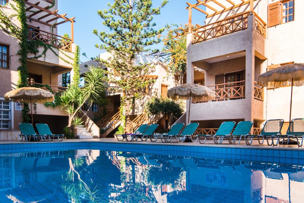 a pool at a hotel with chairs and umbrellas at Anna Maria in Malia