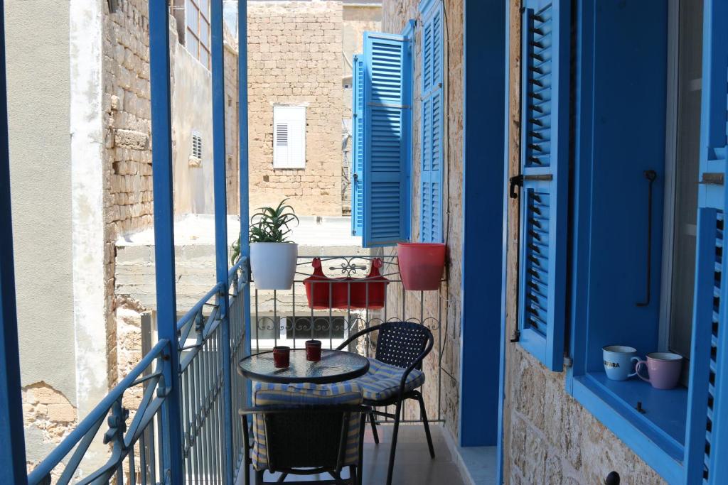 a table and chairs on a balcony with blue windows at Jasmine House in ‘Akko
