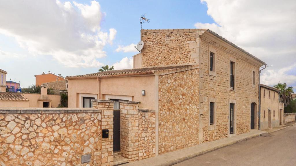 a brick building with a stone wall next to a street at Pool House Marineta in Es Llombards
