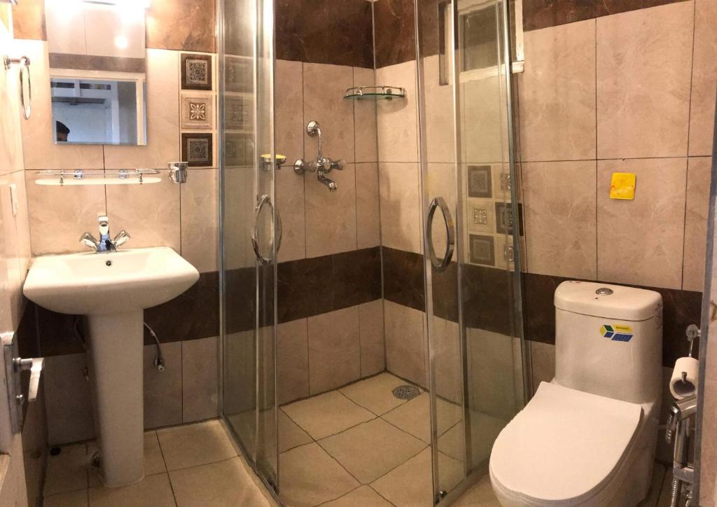 ein Bad mit einer Dusche, einem WC und einem Waschbecken in der Unterkunft Mone's Mountain View Hotel in Kāskī