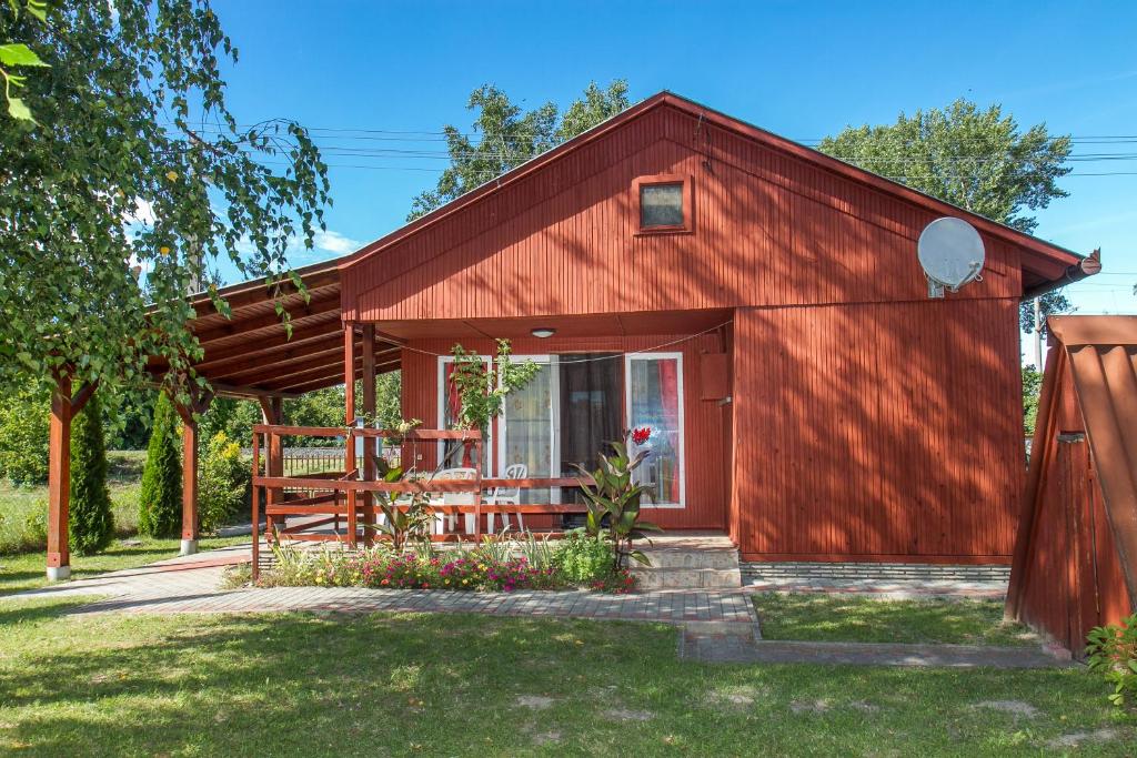 eine rote Scheune mit einer Terrasse im Hof in der Unterkunft Familia Nyaraló 180 in Balatonmáriafürdő