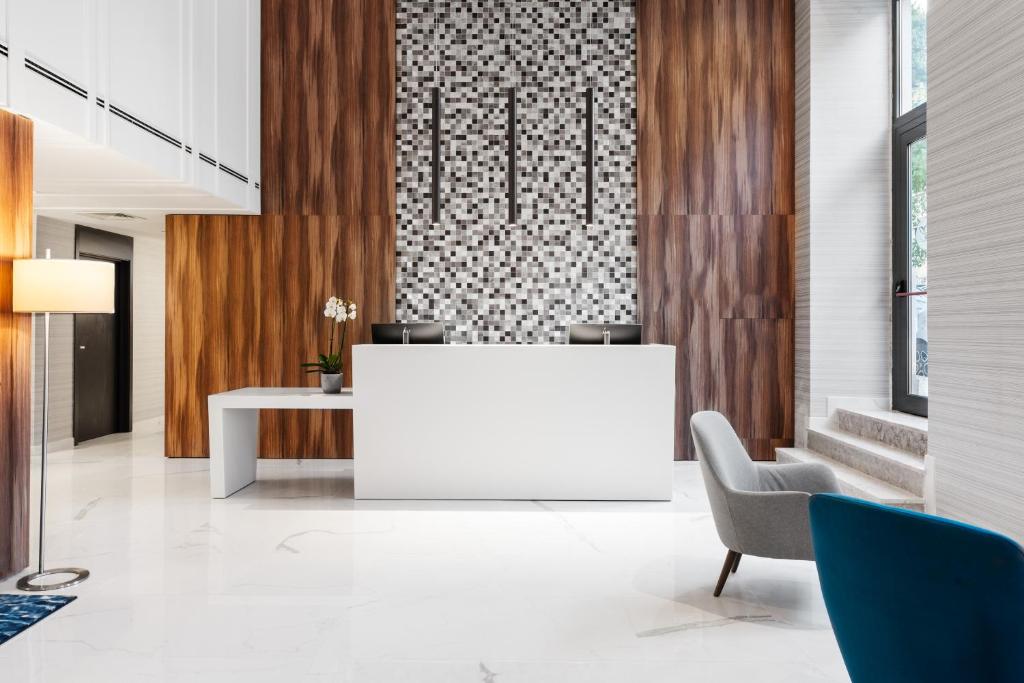 A close view of the white reception desk beneath a mosaic and wood-panel feature wall.