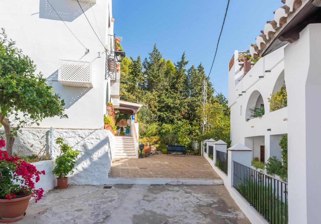 an alleyway between two buildings with flowers at Hostal El Escudo de Mijas in Mijas